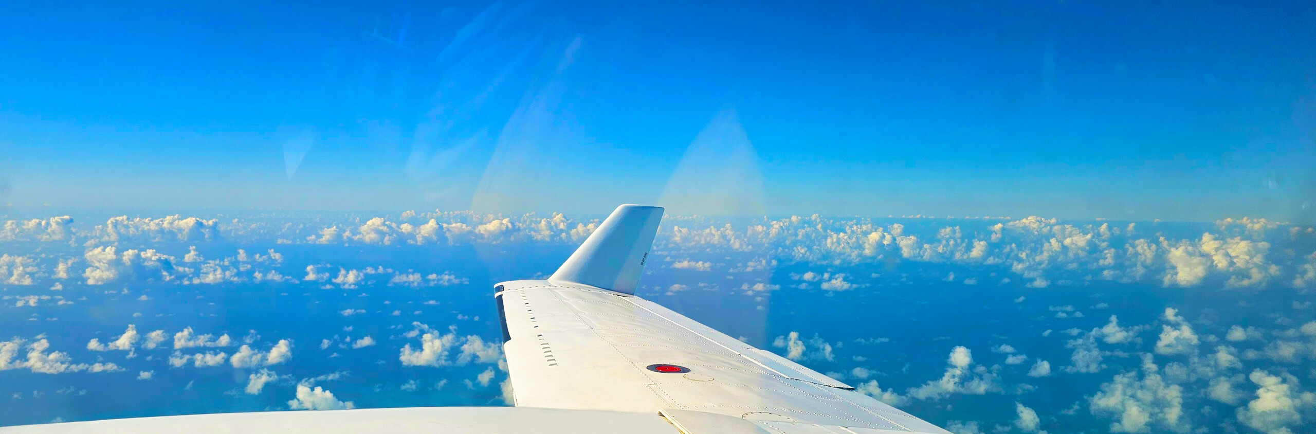 The wing of our Navajo Chieftain soaring across the blue sky over the Caribbean, on the way to one of our Destinations